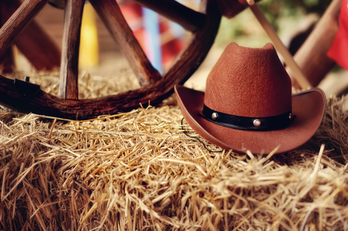 A cowboy hat on a bale of hay like you might find with a mechanical bull 